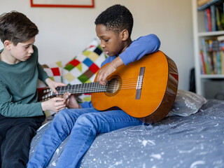 Boy friends (8-9, 10-11) playing guitar at home
