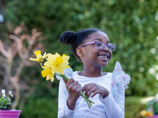 Smiling girl (6-7) holding daffodils outdoors