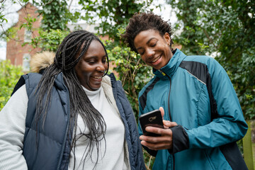 Mother and daughter looking at smart phone in park during walk