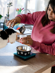 Woman weighing cat food in kitchen