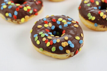 Set of Brown chocolate donut decorated with smarties isolated on white background side view. Fried dough confection, dessert food, sweet snack with chocolate glazing and candies. Selective focus