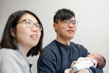 Two parents with baby daughter (1-0 months) at home