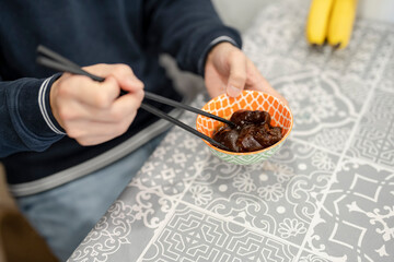 Man eating pork knuckle with ginger vinegar at home