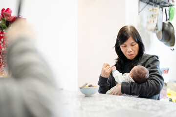 Grandmother holding baby girl (0-1 months) in kitchen