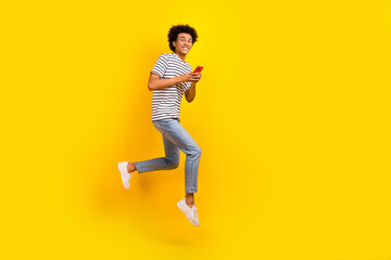 Fototapeta na wymiar Full body photo of young running guy hold phone comfortable using apple iphone jumping download apps isolated on yellow color background