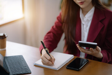 Business woman take notes and use the calculator with calculations about the expenses at the office.