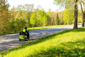 Senior man driving a electric tricycle down the road on a sunny day