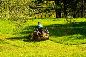 Landscaper cutting grass on riding lawn mower - obrazy, fototapety, plakaty
