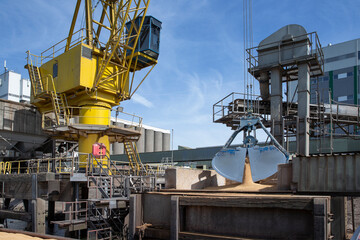 Unloading a ship of soja beans by crane. Barge. Inland vessel. River. Transport by ship. Cattle feed.