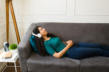 Fototapeta premium Attractive woman listening to meditation music on the couch