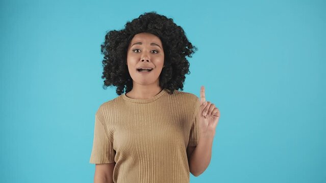 A Woman Standing Against A Blue Background Waving Her Finger While Looking At The Camera. Young Black Woman Waving Her Finger In Denial.