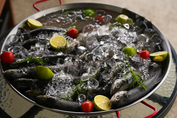 Platter with a lot of trout fresh fish in ice with lemon, prepared to be cooked on the grill