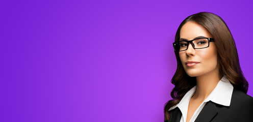 Portrait of happy smiling young businesswoman in eye glasses spectacles, black confident suit, isolated on violet purple background. Business woman in eyeglasses at studio. Copy space area.