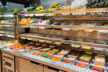 The refrigerated storage cabinet is filled with various vegetables and meats for freshness. Food in...