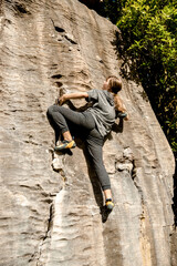 young active teen girl doing outdoor rock climbing bouldering on natural cliff. High quality photo