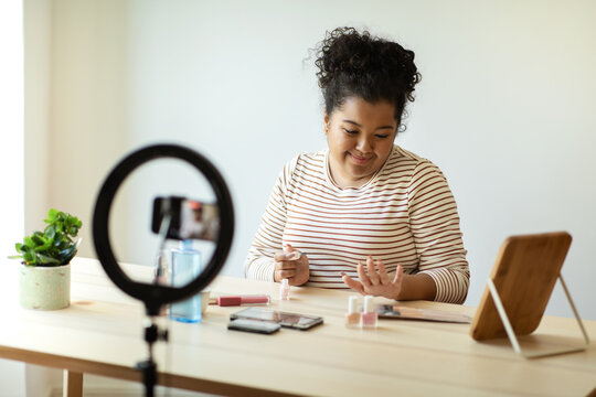 Attractive overweight woman makeup artist recording video while doing manicure