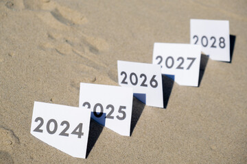 Paper cards with numbers of years from 2024 to 2028 in a row. New year start concept. Resolution time is flying plan goal motivation countdown - obrazy, fototapety, plakaty