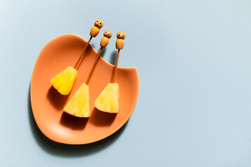 Three slices of fresh pinapple with funny cocktail sticks presented on vintage plate.