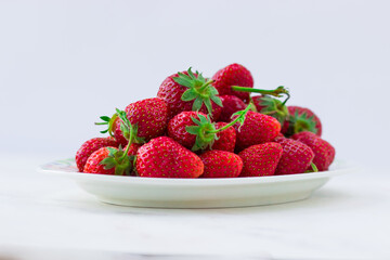 Ripe strawberries on a plate on a white background. Summer berries