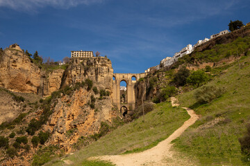 The famous bridge with arched vaults between the rocks of the gorge on a sunny day. Landmark of the city of Ronda, Andalusia, Spain