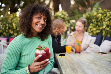 Portrait of beautiful Brazilian mature woman outside gathering with girlfriends in a bar, looking at camera cheerfully.