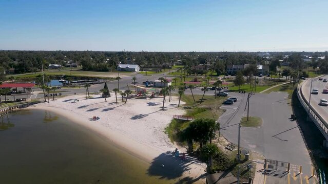 Dropping drone view of Leslie Porter Wayside Park and playground in Lynn Haven from Old Bailey Bridge with birds flying towards camera.