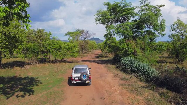 drone follow shot of a 4X4 Jeep driving  in Omo Valley in the savanna Jungle