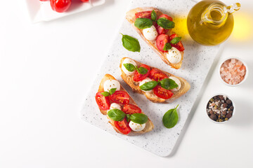 Tomato, basil and mozzarella cheese fresh made caprese bruschetta. Italian tapas, antipasti with vegetables, herbs and oil on grilled ciabatta and baguette bread. Open sandwich.