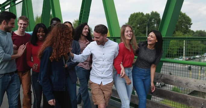 Multiracial young friends having fun walking on the bridge in the city