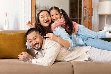 Portrait Of Happy Japanese Family Lying Piled Up At Home