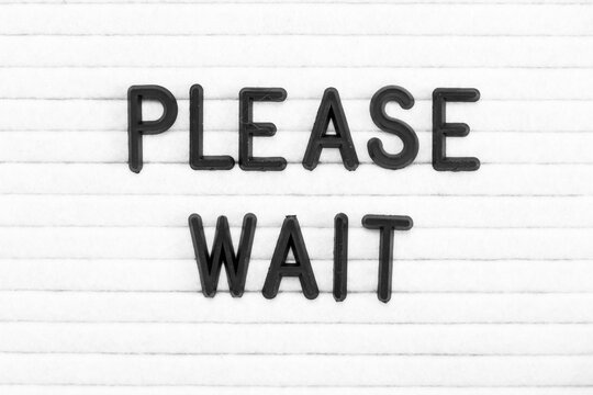 Black color letter in word please wait on white felt board background