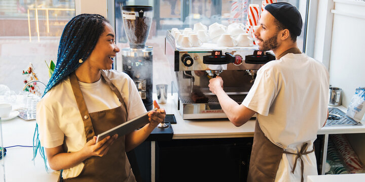 Happy Pretty Waitress Holding Tablet While Talking With Barista In Coffee Shop