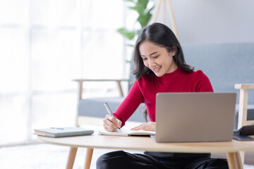 Beautiful Young asian woman at home sitting on the sofa while using laptop and headphone at home