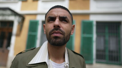 Closeup face of an Arab man with thoughtful expression. A Pensive male person standing outside in with serious contemplative brooding emotion