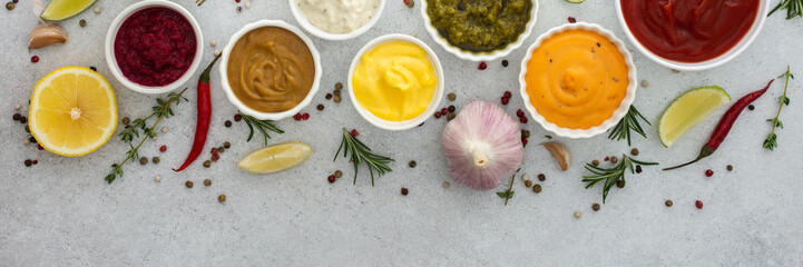 Different types of sauces in bowls with seasonings banner, rosemary and pepper, thyme and garlic, lime and lemon, cilantro, top view, copy space