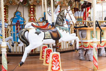 Fototapeta na wymiar Children's vintage carousel with figures of horses. A working carousel without people. Colorful fair carousel on the square.