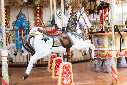 Children's vintage carousel with figures of horses. A working carousel without people. Colorful fair carousel on the square.