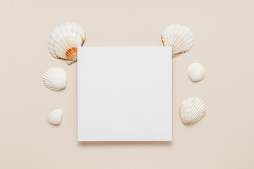 Empty paper sheet card with seashells on neutral beige background. Summer aesthetic minimal card for invitation, greeting, wedding and design, top view, flat lay