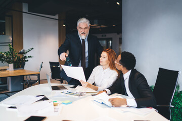 Multiethnic coworkers reading papers with male leader in office