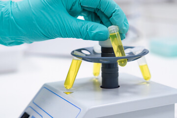A scientist places a test tube into a microcentrifuge for the purpose of shaking or centrifuging samples intended for DNA analysis.