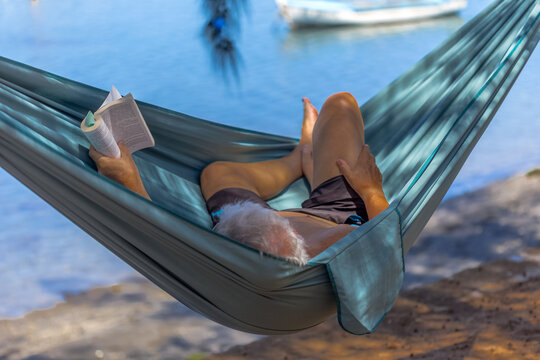 Senior lisant dans un hamac sur la plage 