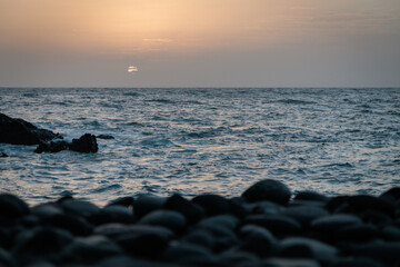 Sunset and Atlantic Ocean. Black volcanic pebbles of Tenerife Coast. .