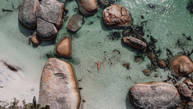 Aerial picture of a girl swimming in a fairy pool in Albany, Australia. Shallow and transparent water. Drone picture. Swimming in paradise in blue water between rocks.