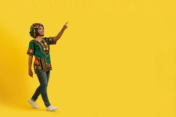 Pretty african lady in colorful outwear pointing at copy space