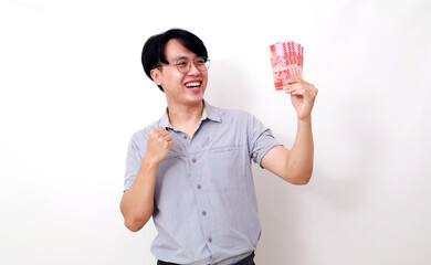 Happy asian man holding Indonesian banknotes while showing clenching hand