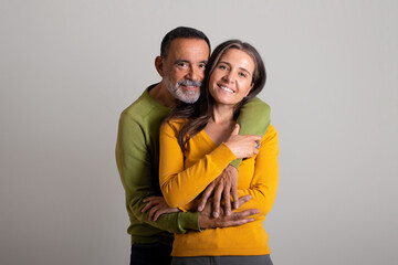 Fototapeta premium Positive caucasian elderly husband hugging his wife, enjoy romantic date and spare time