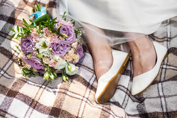 Bride's feet and wedding bouquet on brown blanket. Small rustic wedding, micro wedding
