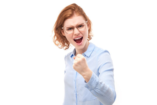 Portrait angry redhead young woman screaming isolated on white studio background, showing negative emotions.