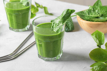 Healthy green smoothie with spinach, avocado, banana, and vegan milk in two glasses and fresh ingredients on light table