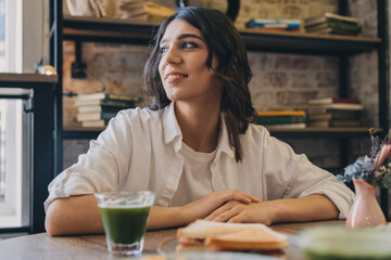 Portrait of a young attractive dark-haired woman eating a sandwich in a cafe.